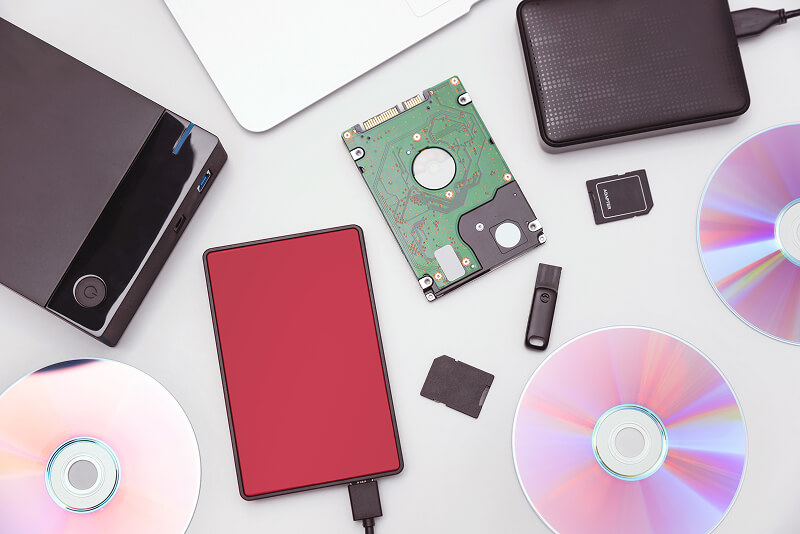 An image of multiple storage media, including external hard drives, USB flash drives, and optical discs.