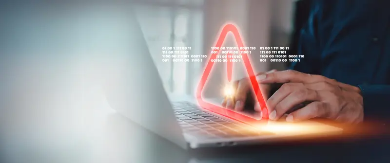 person typing on laptop with red security icon over screen