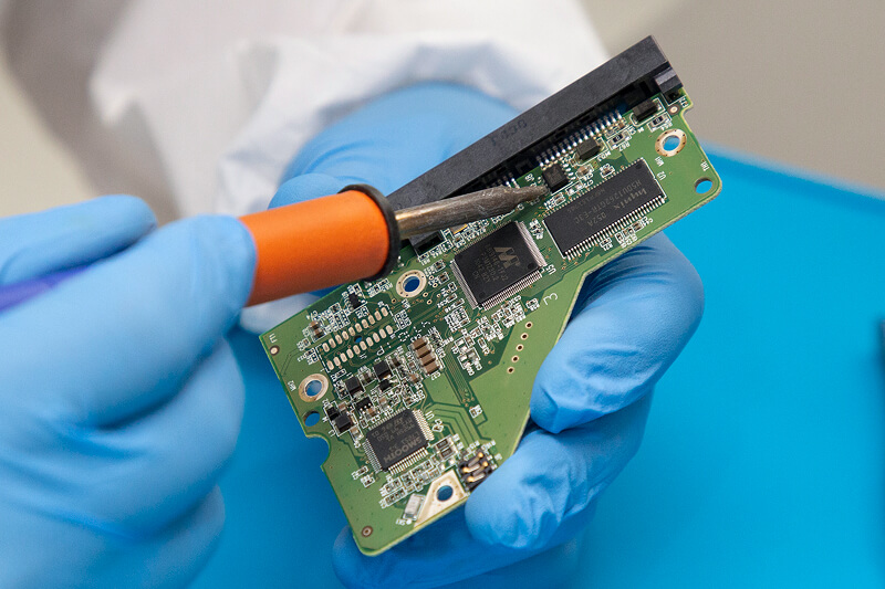 An image of an engineer handling component-level repair on a hard drive’s circuit board.